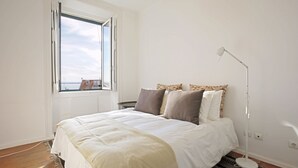 Un dormitorio con una cama grande, una ventana con vistas y una lámpara de pie.