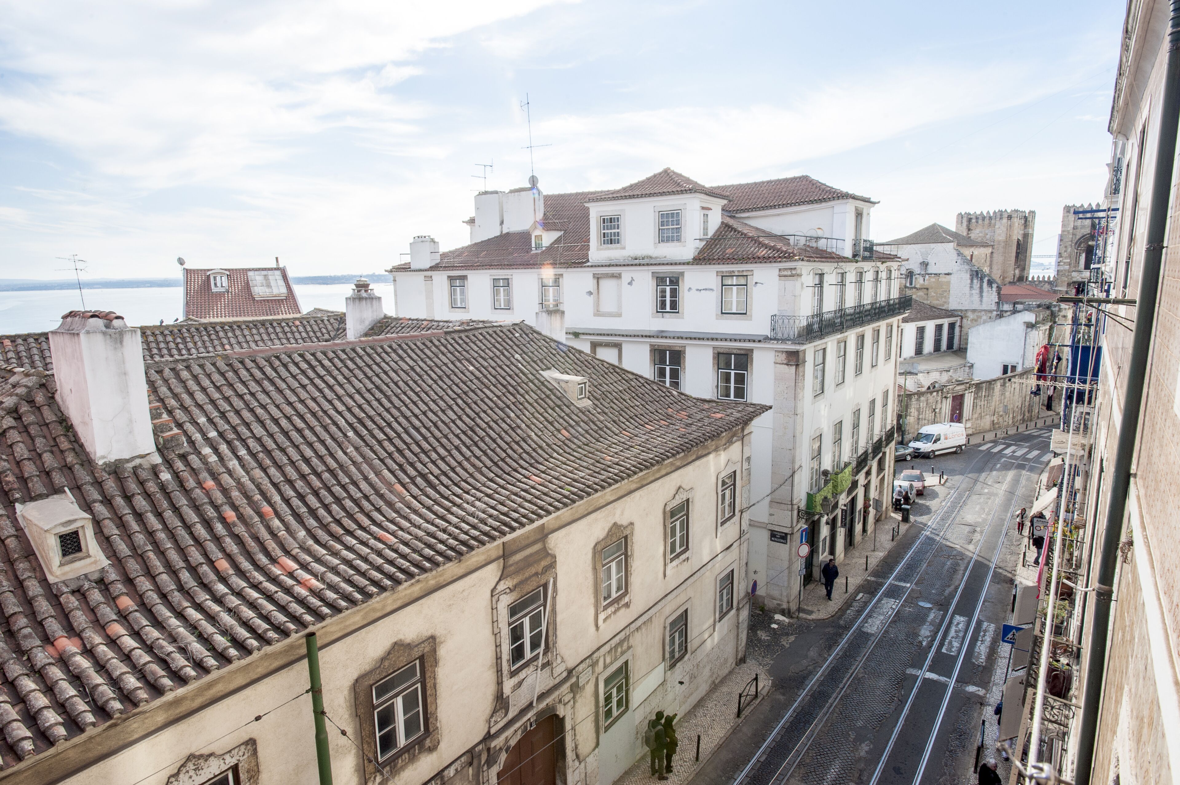A street view with buildings, a clear sky, and a body of water in the distance.
