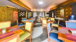 A hotel dining area with multiple tables and chairs, a bar area, and a counter with a water dispenser. - OYO 902 Comfy Inn Manila (Manila)
