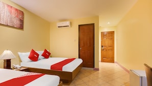 A hotel room with two beds, a wooden door, an air conditioning unit, a lamp, and a refrigerator. - OYO 902 Comfy Inn Manila (Manila)