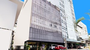 A modern building with a glass facade, a ground-level entrance, and a visible sign for a hotel. - OYO 902 Comfy Inn Manila (Manila)