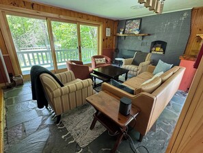 A cozy living room with a stone floor, wooden furniture, and a fireplace.