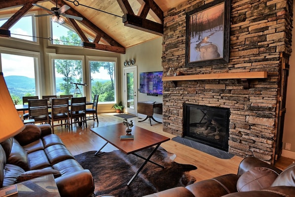 A living room with a stone fireplace, leather furniture, and a large TV.