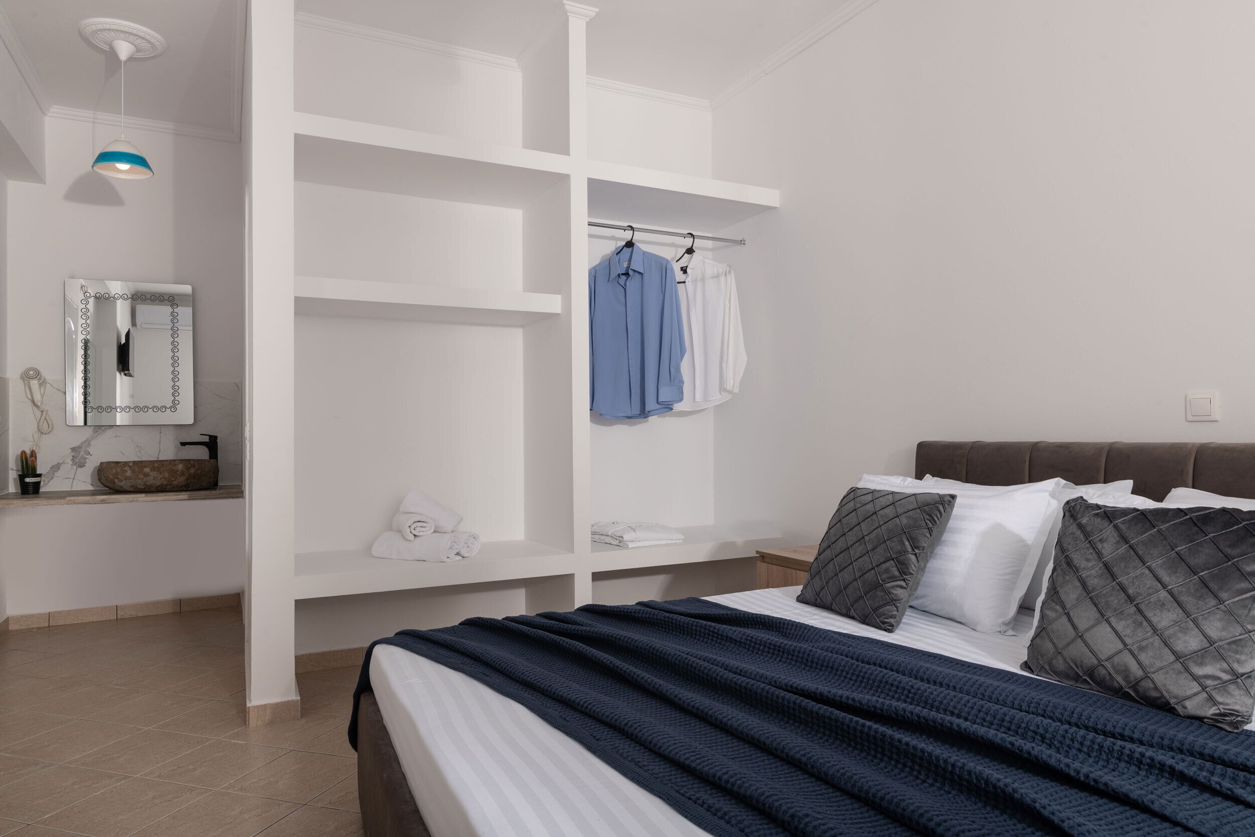 Une chambre à coucher comprenant un lit, une armoire, un miroir et un luminaire suspendu.