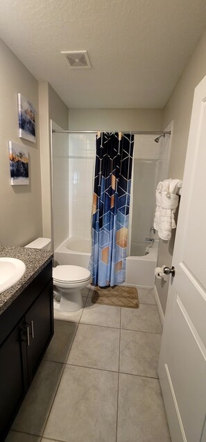 Een bad/douchecombinatie, een haardroger, handdoeken, zeep