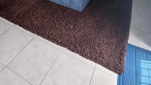 Uma sala de estar com sofá seccional, ventilador de teto e arte abstrata nas paredes.