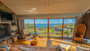 Un salón amplio con un sofá grande, una chimenea y vistas al mar.