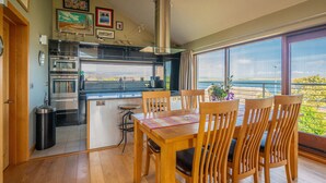 Una cocina moderna con comedor, piso de madera y ventanas amplias con vistas panorámicas.