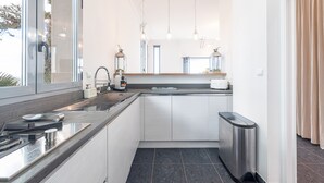 Eine moderne Küche mit einem Edelstahl-Spülbecken, einem eingebauten Backofen und einer kleinen Mülltonne.