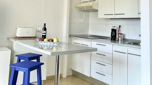 A modern kitchen with white cabinets, a countertop, a blue stool, and a toaster. - Apartment mit Meerblick in Optimaler Lage (Costa Adeje)