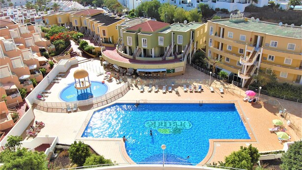 A hotel with a large swimming pool, multiple balconies, and a children's play area. - Apartment mit Meerblick in Optimaler Lage (Costa Adeje)