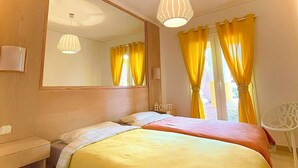 A bedroom with two beds, a large mirror, and a small white chair. - Apartment mit Meerblick in Optimaler Lage (Costa Adeje)