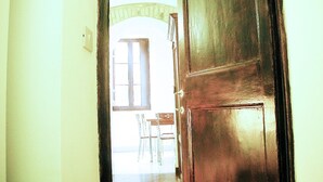 Une porte en bois qui donne sur une pièce avec une fenêtre et une chaise.