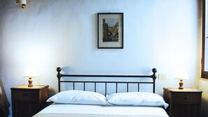 Un lit bien fait, avec une tête de lit, deux tables de chevet avec des lampes et un tableau encadré au mur.