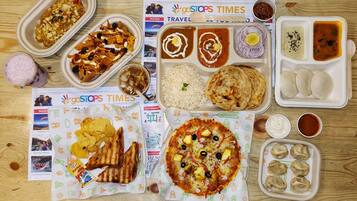 A variety of food items including nachos, rice, flatbread, pizza, and dumplings, arranged on a wooden table.