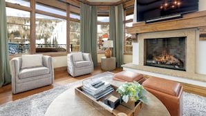 A spacious living room with a fireplace, large windows, and a cozy seating area.