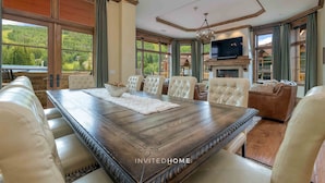 A spacious dining area with a large wooden table, leather chairs, and a fireplace.