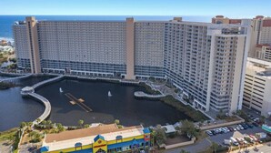 A large hotel with multiple floors, a central courtyard with water features, and a view of the ocean.