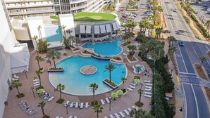 A hotel with multiple swimming pools, sun loungers, and palm trees.