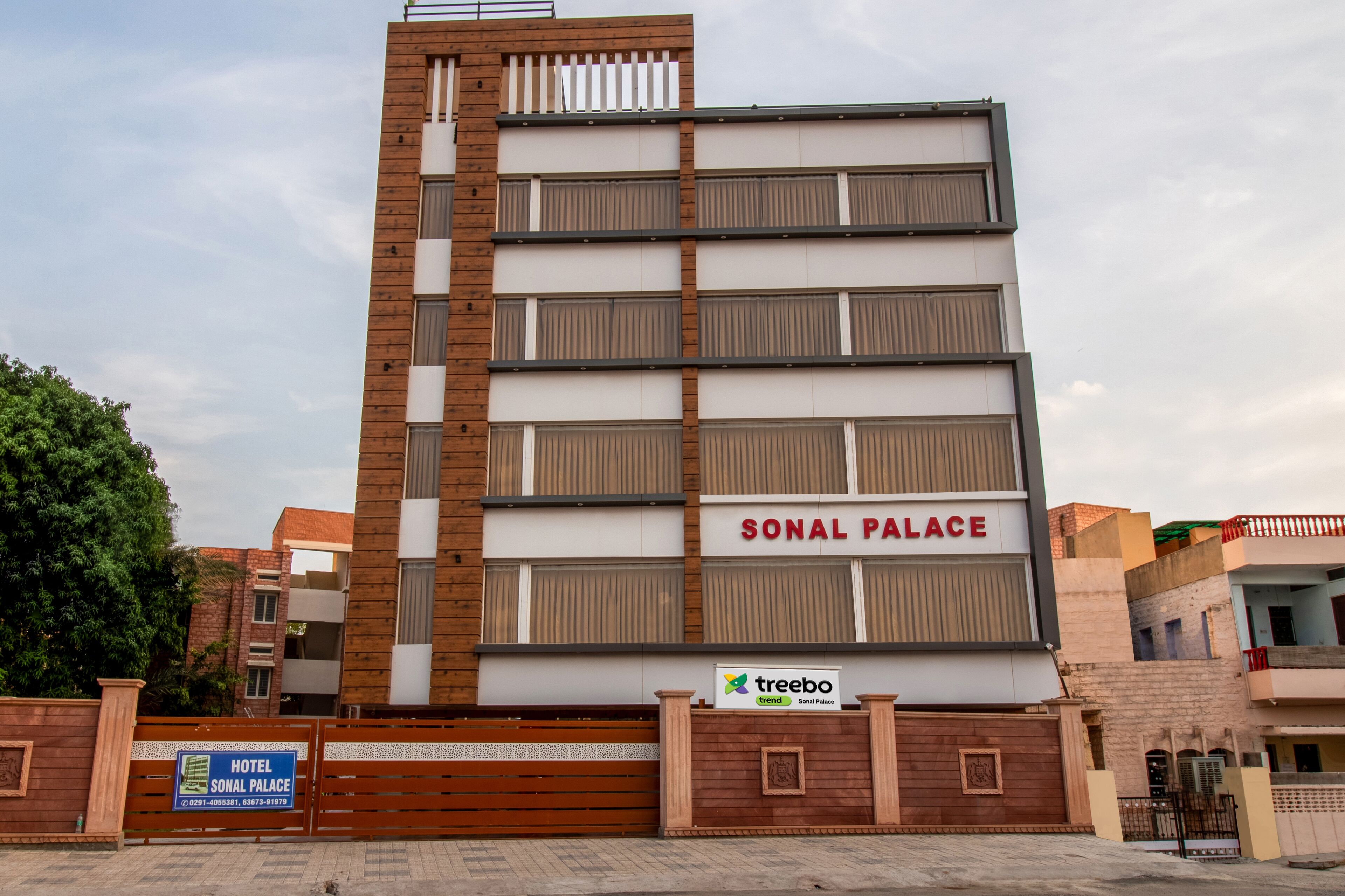 A multi-story hotel named SONAL PALACE with a modern design, featuring a prominent signboard and a tree logo.