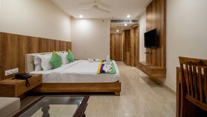 Habitación de hotel con cama, mesita de noche, televisor, paneles de madera y ventilador de techo.