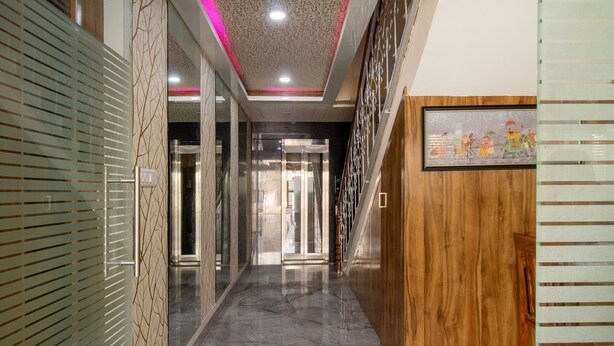 Un pasillo con piso de mármol, puertas de vidrio y panel de madera.