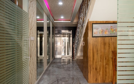 A hallway with a marble floor, glass doors, and a wooden panel wall.