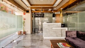 Un área de recepción con un mostrador de mármol, un sofá púrpura y un ventilador de techo.