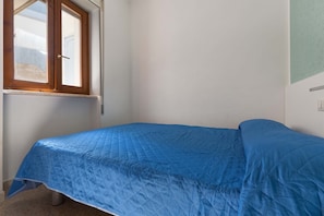 Une chambre avec un lit simple, une fenêtre et un interrupteur fixé au mur.