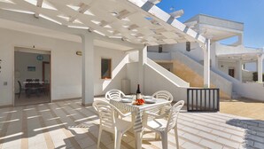 A patio with a table set for dining, a pergola overhead, and a staircase leading to an upper level. - 2241 Residence Anna - Appartamento Aragosta by Barbarhouse (Taviano)