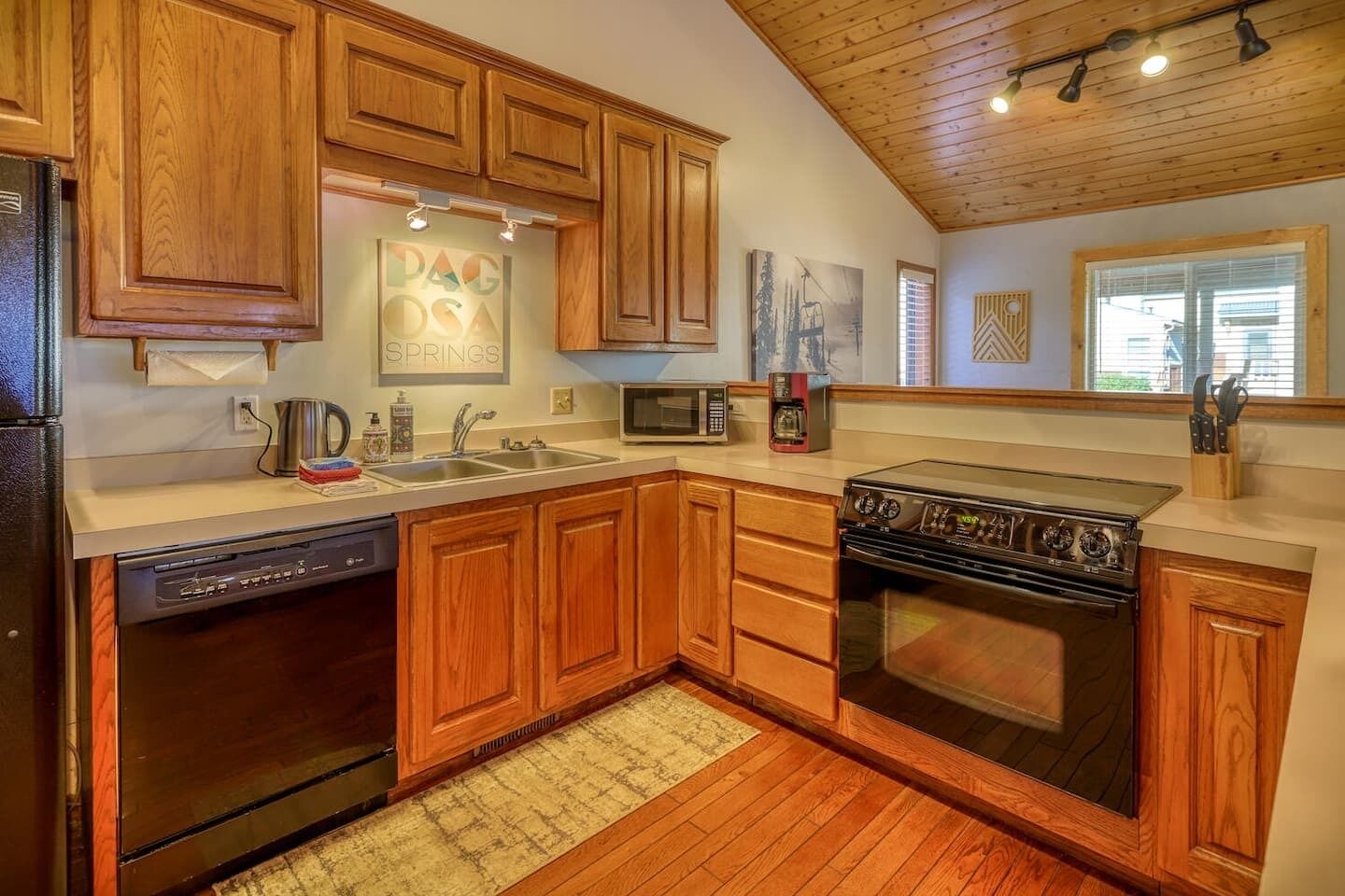 A kitchen with wooden cabinets, a stainless steel refrigerator, a dishwasher, a microwave, a stove, and a sink.