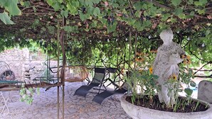 A pergola with vines, a stone statue, and outdoor seating.
