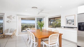 A modern kitchen with a dining area, a view of the outdoors, and a ceiling fan.