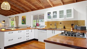 Een moderne keuken met witte kastjes, een houten aanrecht en een gasfornuis.