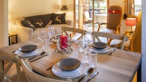 A dining area with a wooden table set for four, including plates, cutlery, and glasses. - Chalet Sans Soucis by Interhome (Villars)