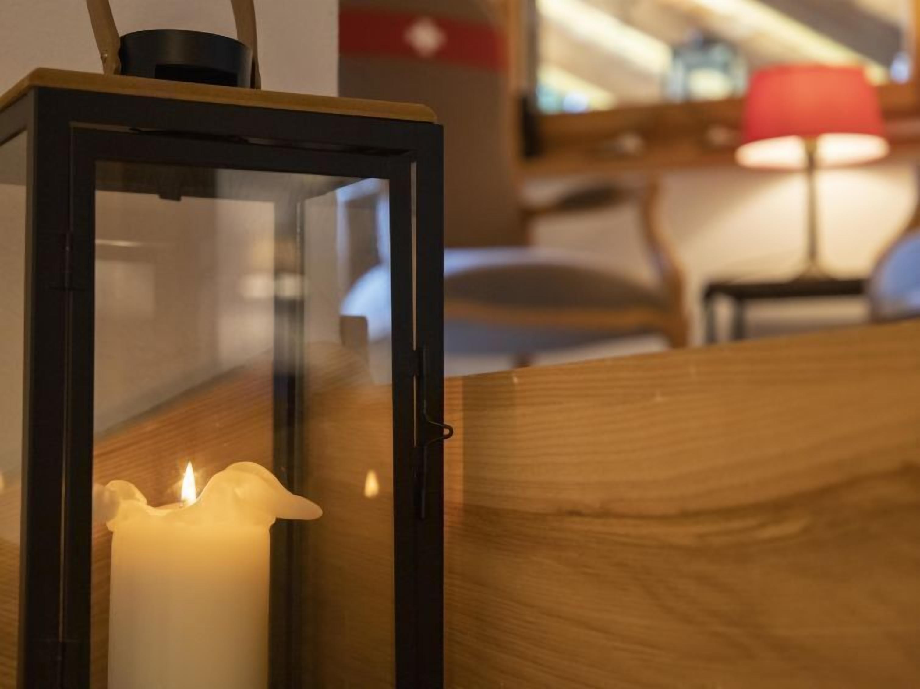 Une bougie à l’intérieur d’une lanterne noire posée sur une surface en bois.