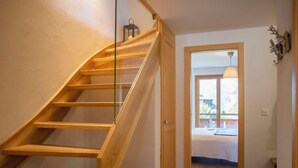 A wooden staircase leading to a bedroom with a bed and a window. - Chalet Sans Soucis by Interhome (Villars)