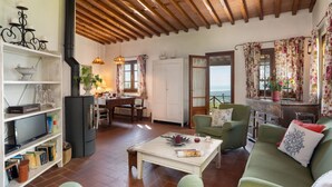 Un soggiorno accogliente con soffitto in legno, un'area pranzo con tavolo e sedie, e vista sul mare attraverso una finestra.