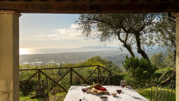 Zona pranzo all'aperto con tavolo apparecchiato per due, con vista su un paesaggio suggestivo.