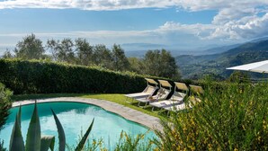 Una piscina con lettini e vista sulle montagne.
