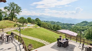 Un patio con mobiliario exterior, piscina y una vista panorámica a las montañas.