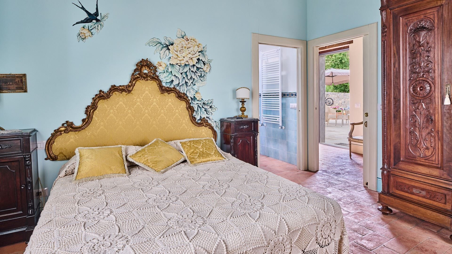 Une chambre avec un grand lit, une armoire en bois et une décoration murale à motifs floraux.