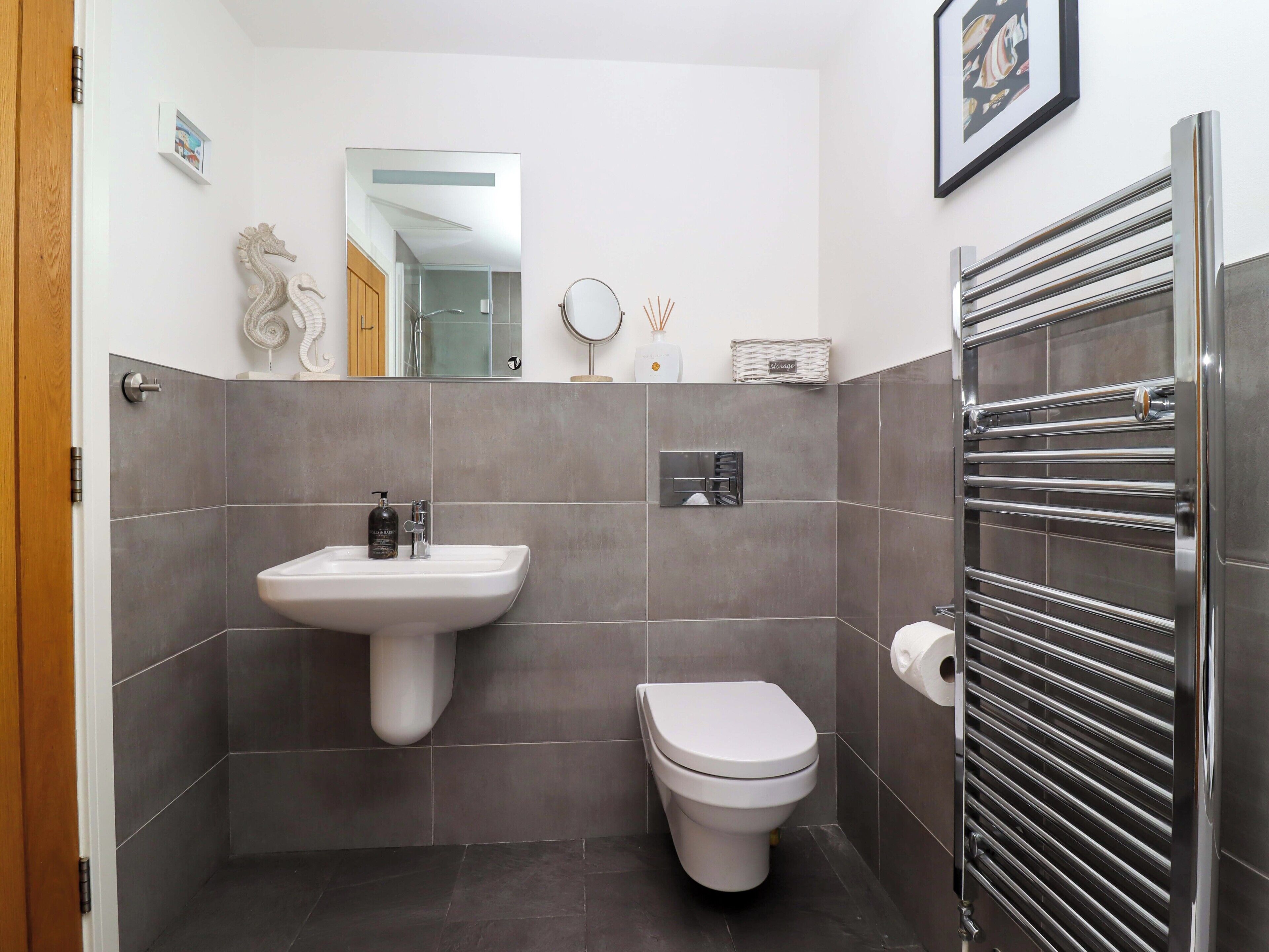 A compact bathroom with a pedestal sink, toilet, and a towel rack.