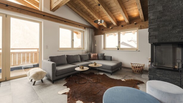 Een moderne woonkamer met een modulaire bank, een stenen openhaard en grote ramen.