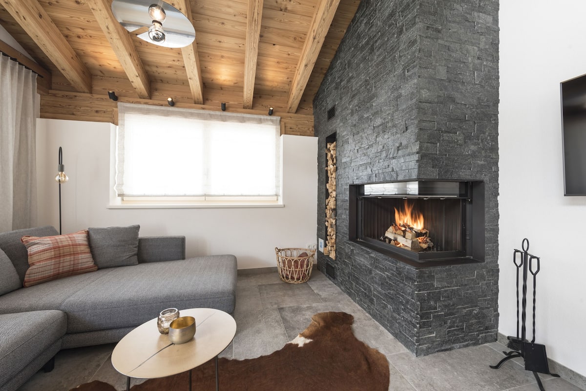 Ein gemütliches Wohnzimmer mit Kamin aus Stein, einer Couch, einem Couchtisch und einem Cowhide-Teppich.