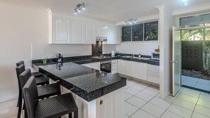 A modern kitchen with white cabinets, a granite countertop, and a built-in stove.