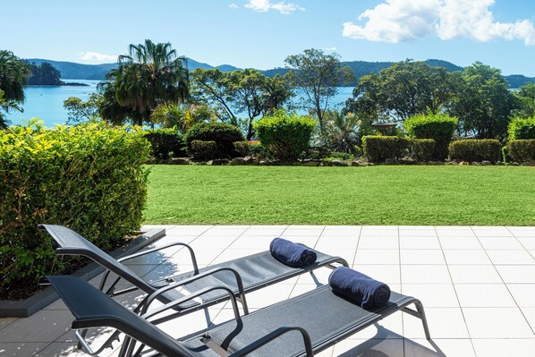 A patio with lounge chairs and a view of a lake and mountains. - Lagoon Lodge 003, Lagoon Lodge 003 on Hamilton Island (Hamilton Island)