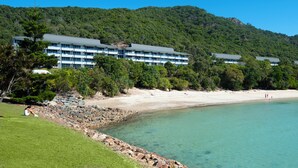 A beachfront hotel with multiple buildings, a sandy beach, and a clear blue sea.