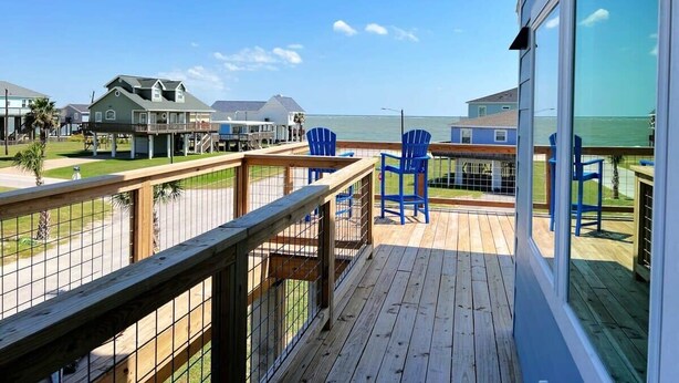 Une terrasse en bois avec des chaises bleues donnant sur une plage.