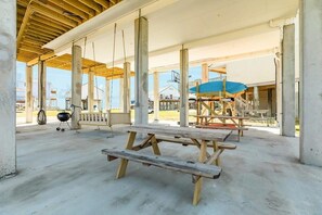A covered outdoor area with picnic tables, a barbecue grill, and a blue canopy structure.